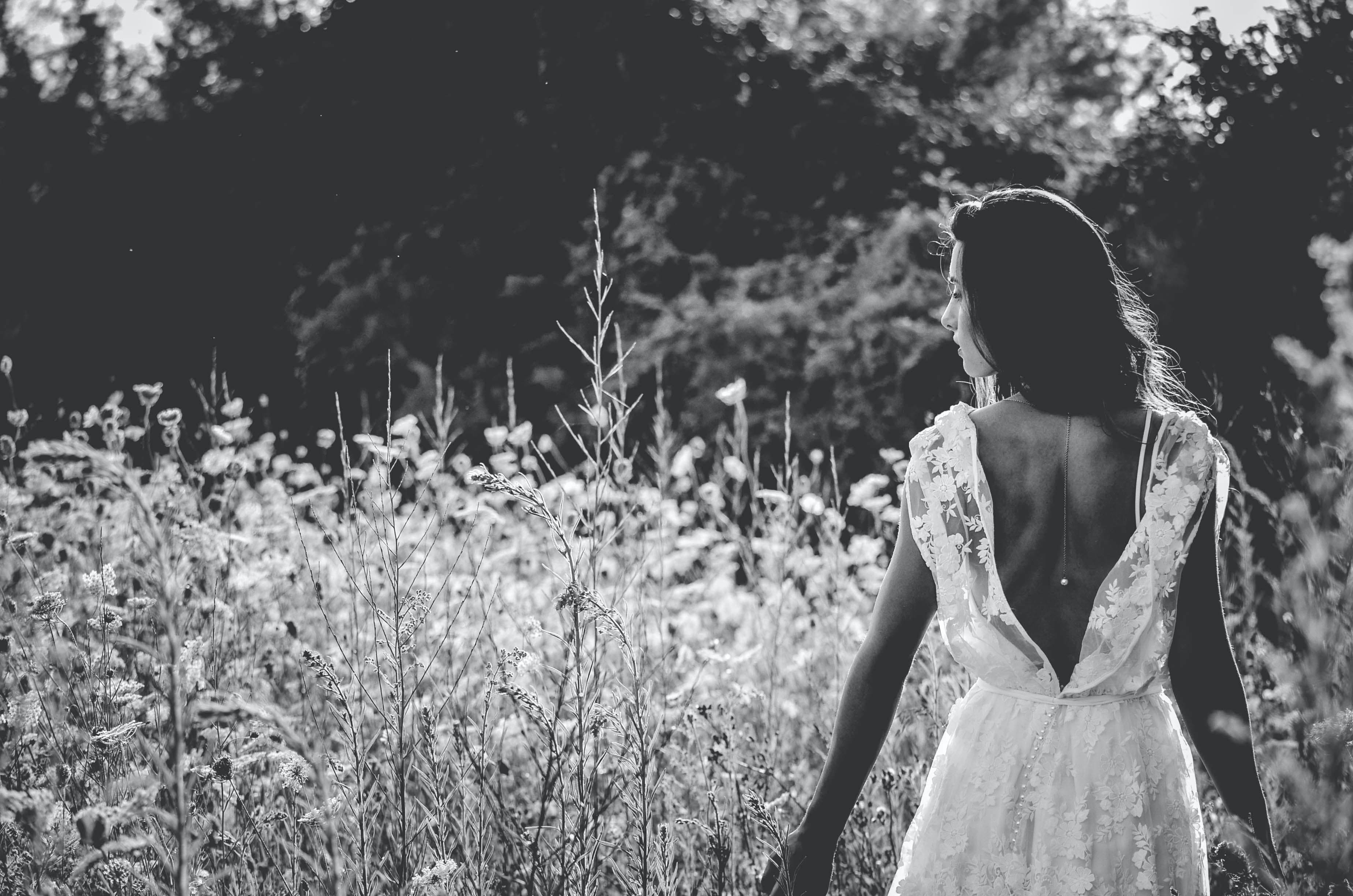 A bride in a backless lace gown standing among wildflowers